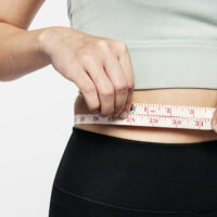 Active woman measuring her waist